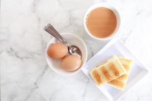 kaya pan tostado, huevo y té en la mesa foto