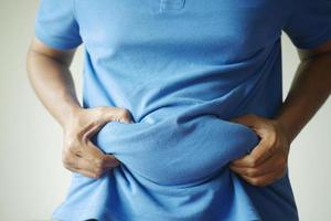 man's hand holding excessive belly fat, overweight concept photo