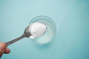 pouring white sugar in a glass of water on table photo