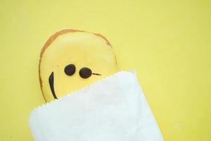 diseño de cara sonriente donut y paquete sobre fondo amarillo foto