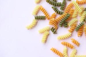 Organic fusilli tricolore spilling on pink background photo