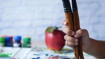 Kid holds big paintbrushes close up video