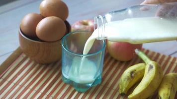 derramando leite em um copo, uma tigela com ovos, bananas e maçãs video