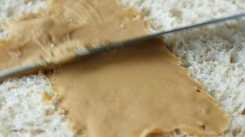 Macro shot of spreding peanut butter onto a slice of bread video