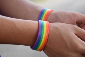 Rainbow wristband wearing in hand of young asian gay to show and represent gender diversity, to respect human rights in alternative sex, to stop punishing homosexuals in some religions photo