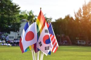 banderas del arco iris y banderas de muchos países frente al césped verde de la escuela asiática, concepto para la celebración de los géneros lgbtq en el mes del orgullo en todo el mundo, enfoque suave y selectivo. foto