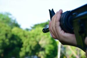 pistola de airsoft o pistola de bb sosteniéndose en las manos del tirador mientras apunta al objetivo de destino en el campo de entrenamiento de pistola de bb o pistola de airsoft, enfoque suave y selectivo, concepto para tiempos libres y pasatiempos al aire libre. foto