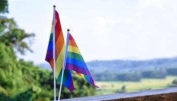 LGBT rainbow flag waving and holding in hands against blue sky in afternoon of the day, soft and selective focus, concept for lgbtqai celebration in pride month around the world. photo