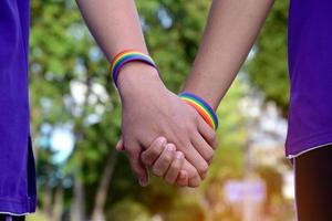 Rainbow wristband wearing in hand of young asian gay to show and represent gender diversity, to respect human rights in alternative sex, to stop punishing homosexuals in some religions photo