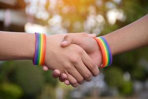 Rainbow wristband wearing in hand of young asian gay to show and represent gender diversity, to respect human rights in alternative sex, to stop punishing homosexuals in some religions photo