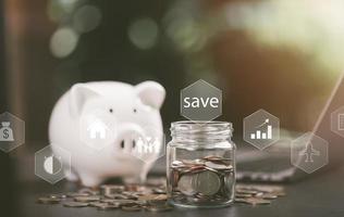 Glass jar, coin money, white pig piggy bank, all on the table, finance and banking, fund growth and savings concept, proportional money management to spend effectively photo