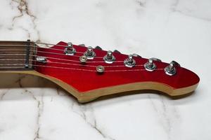 Neck of a red electric guitar isolated on marble background photo