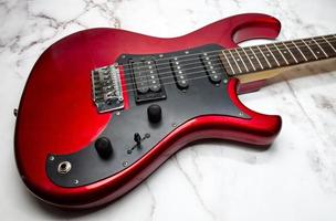 Red electric guitar isolated on marble background photo