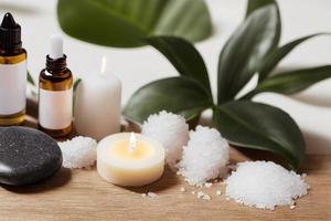 artículos de tratamiento de belleza para procedimientos de spa en mesa de madera blanca con planta verde. piedras de masaje, aceites esenciales y sal marina con velas encendidas. foto