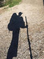 Shadow of a hiker with multiple backpacks and hiking stick photo