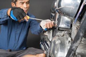 People are repairing a motorcycle Use a wrench and a screwdriver to work photo