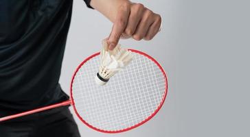 A badminton player in sportswear stands holding a racket and shuttlecock photo