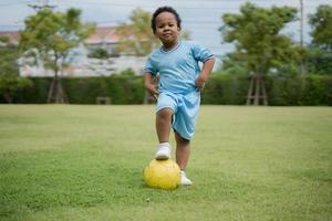 lindo niño con pelota de fútbol en el parque en un día soleado. foto