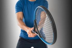 A male tennis player holding a tennis racket with a determined expression and eyes on a white background. photo