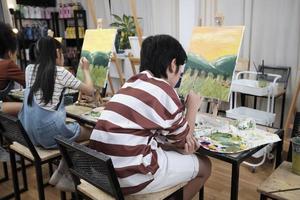 A group of student kids concentrates on acrylic color picture painting with a paintbrush on canvas in art classroom, creatively learning with talents and skills at elementary school studio education. photo