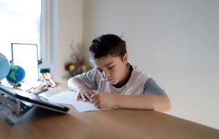 Education concept,School kid using grey colour pen drawing or sketching on paper,Portrait  boy siting on table doing homework in living room,Child enjoy art and craft activity at home on weekend, photo