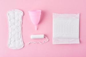 toalla sanitaria, copa menstrual y tampón sobre un fondo rosa, vista superior foto