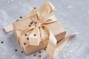 Gift box with golden bow and confetti, close up photo