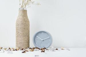 Classic alarm clock, flower branch and petals on a white table. photo