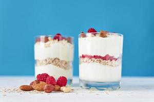 dos vasos de granola de yogur griego con frambuesas, copos de avena y nueces