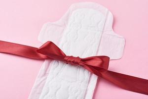 Sanitary pad and red ribbon on a pink background photo