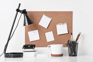 Cork board with office supplies on white background photo