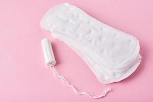 toalla sanitaria y tampón menstrual sobre un fondo rosa foto