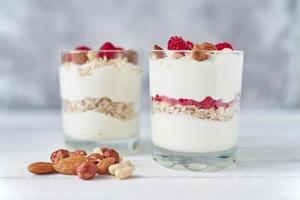 dos vasos de granola de yogur griego con frambuesas, copos de avena y nueces