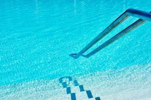 Background of water in blue swimming pool, water surface with a sun reflection photo