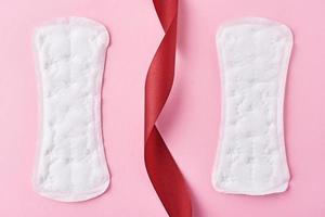 Two sanitary pads and red ribbon on a pink background photo
