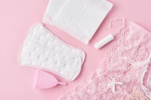 toallas sanitarias, copa menstrual, tampones y bragas sobre un fondo rosa foto