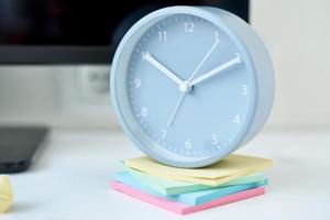 Gray round alarm clock and colorful sticky notes on a white background photo