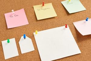 Colorful paper notes with words To do, In progress and Done pinned on a cork board photo