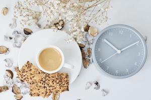 Cup of coffee and classic alarm clock on a white table