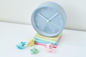 Gray round alarm clock and colorful sticky notes on a white background photo