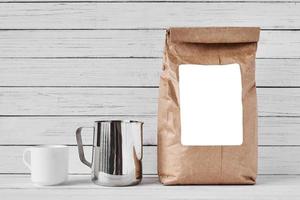 Coffee cup, craft paper bag and stainless pitcher photo