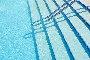 fondo de agua en la piscina azul, superficie de agua con un reflejo del sol foto