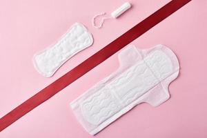 Two sanitary pads and red ribbon on a pink background photo