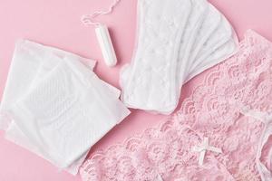 Sanitary pad, menstrual cup, tampon and panties on a pink background photo