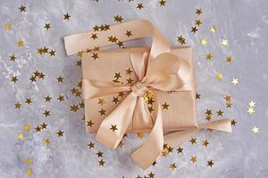 Gift box with golden bow and confetti, close up photo