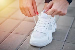 mujer prepárate para correr. manos femeninas atando cordones de zapatos en zapatillas deportivas foto