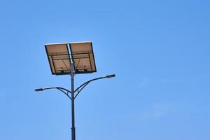 Solar panel on street lamp aganst blue sky photo