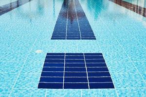 Background of water in blue swimming pool, water surface with a sun reflection photo