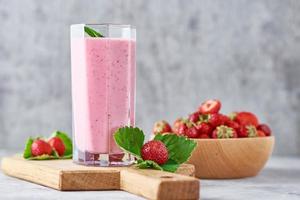 batido de fresa en un frasco de vidrio y fresas frescas con hojas foto