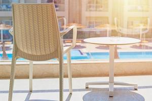 empty chair and table on a balcony against swimming pool background photo